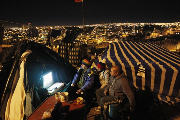 Chilean soccer fans watch the 2014 World Cup match between Chile and Australia in their makeshift tent on the hills of Las Canas in Valparaiso city