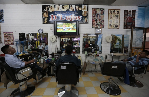 People watch the 2014 World Cup opening soccer match in a barber shop in Guatemala City