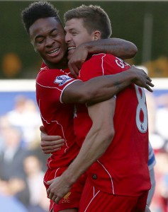 Liverpool's Raheem Sterling celebrates with Steven Gerrard after his cross led to the winning own goal during their English Premier League soccer match against Queens Park Rangers at Loftus Road in London