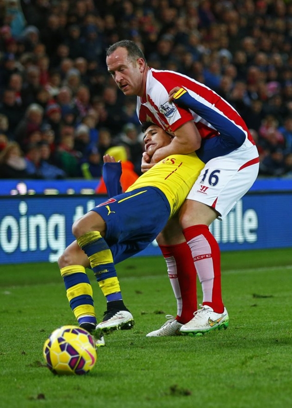 Stoke City's Charlie Adam gets a yellow card for a foul on Arsenal's Alexis Sanchez during their English Premier League soccer match in Stoke