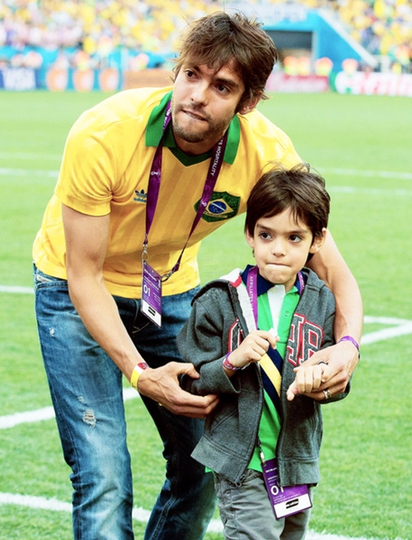 Kaka with his son walks along the pitch before kick off